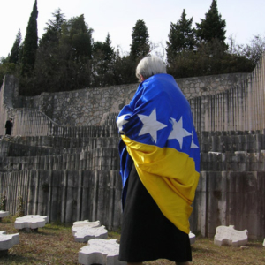 Female former Partisan wrapped in the new Bosnian national flag during a commemoration ceremony at the Partisan Cemetery, Mostar, Bosnia and Herzegovina. (Photo: Monika Palmberger)