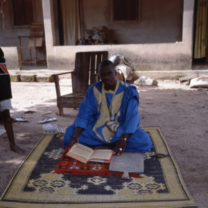 Marabout presenting his Quran and a wooden board with a sura as insignia of his status (Côte d’Ivoire). (Photo: Boris Nieswand)