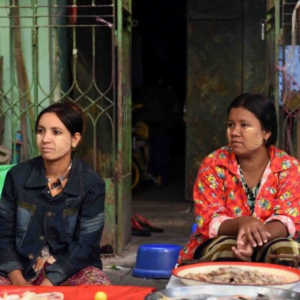 A pair of young fish mongers wearing thanaka waiting for customers. (Photo: Naomi Hellmann)
