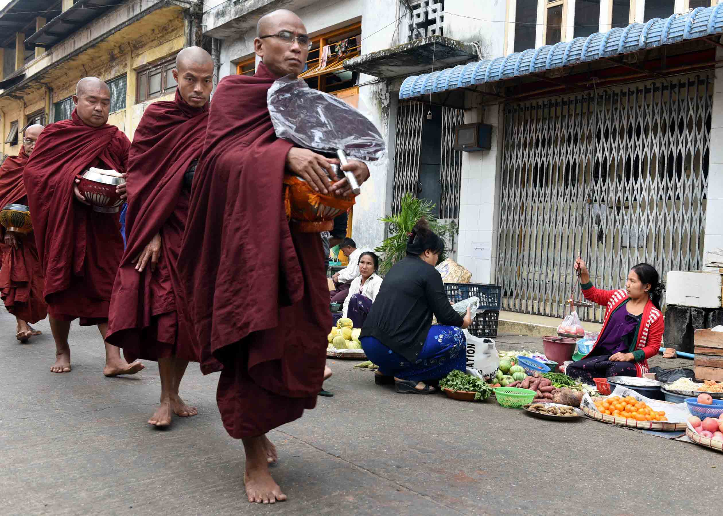 Buddhist monks in crimson robes walk through the streets of Yangon barefoot each morning collecting food, money, and other material offerings from people and bestowing brief prayers in exchange. (Photo: Naomi Hellmann)