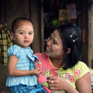 A mother smiles holding her daughter at an outdoor produce market in downtown Yangon. (Photo: Naomi Hellmann)