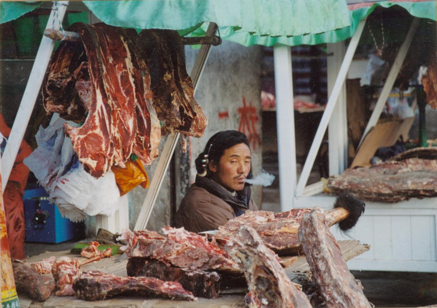 A Tibetan man sells yak meat at an outdoor stall in Lhasa. (Photo: Naomi Hellmann)