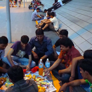 Bangladeshi Muslim migrant men breaking fast along a path to Boon Lay MRT station while commuters continue their journey from work. (Photo: Junjia Ye)