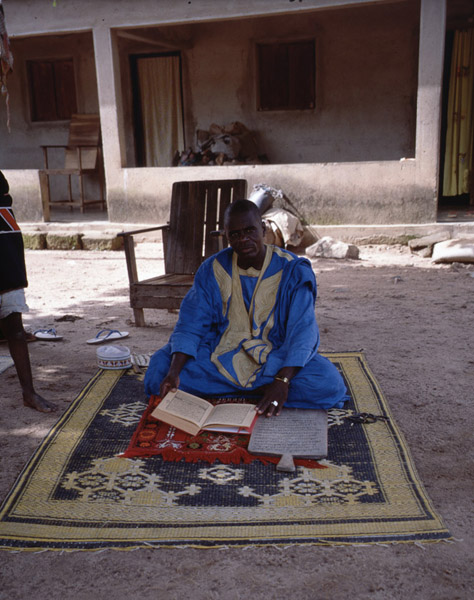 Marabout presenting his Quran and a wooden board with a sura as insignia of his status (Côte d’Ivoire). (Photo: Boris Nieswand)