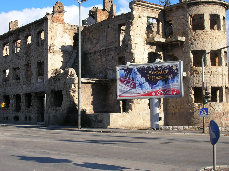 One of the numerous buildings on the former frontline destroyed during the war. In its front billboard ad by Coca Cola Seasons Greetings, Mostar, Bosnia and Herzegovina. (Photo: Monika Palmberger)