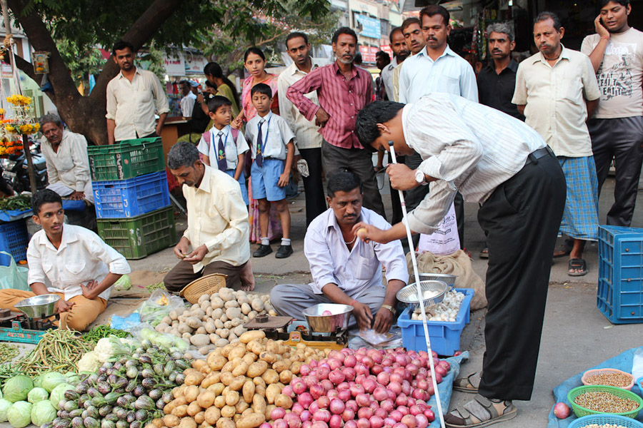 Pradip, who is deaf-blind and one of the research participants, buying vegetables and gesturing with the vegetable seller. (Photo: Annelies Kusters)
